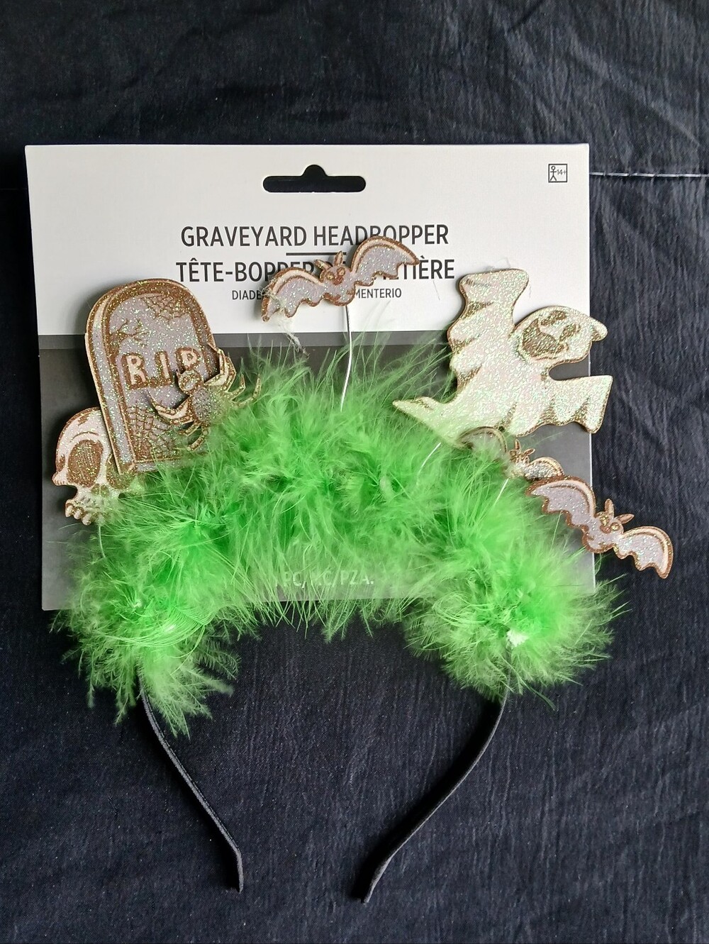 Green feather headband with gold glitter tombstone, bat, and ghost decorations